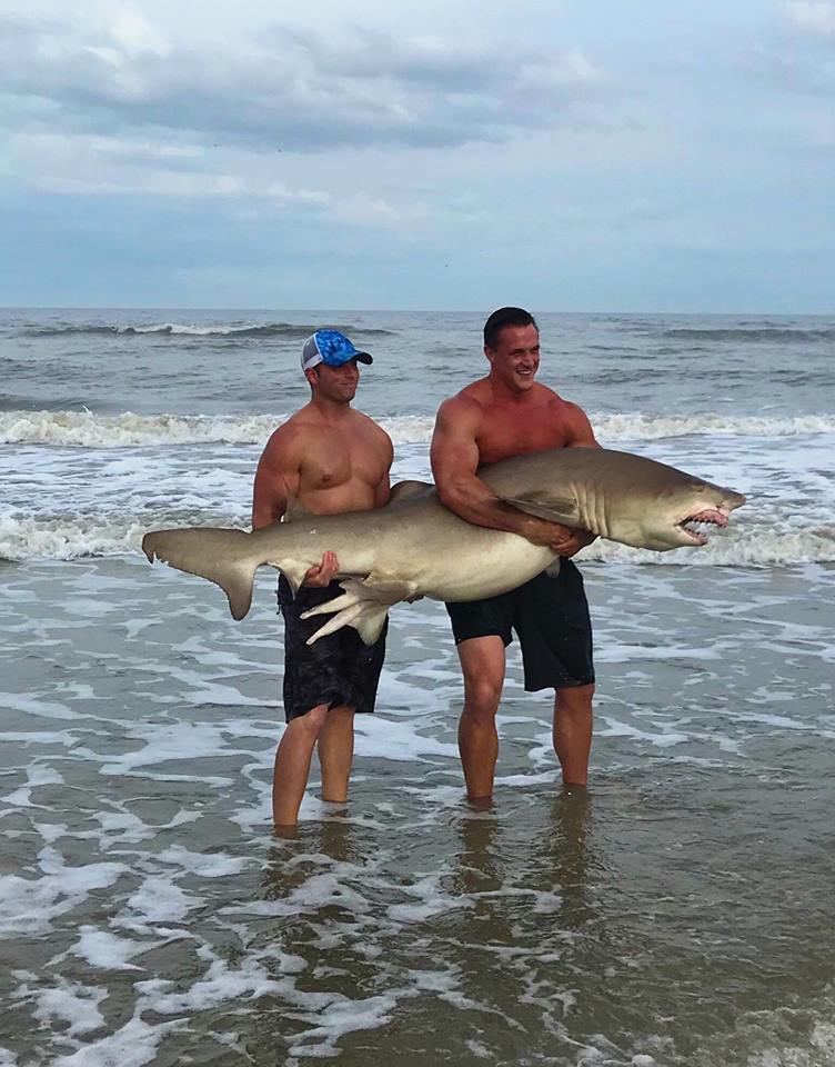 two men holding large shark on atlantic beach florida